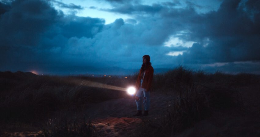 Kobieta na spacerze wieczorem ma w ręce latarke